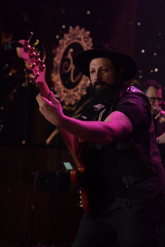 Cantor da Banda iNova de chapéu em apresentação sob luz magenta