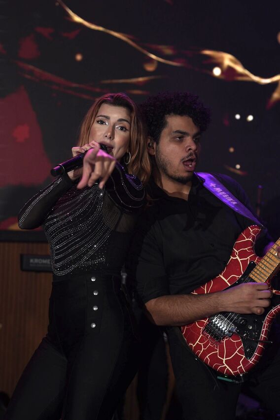Casal de cantores da Banda iNova cantando abraçados no palco