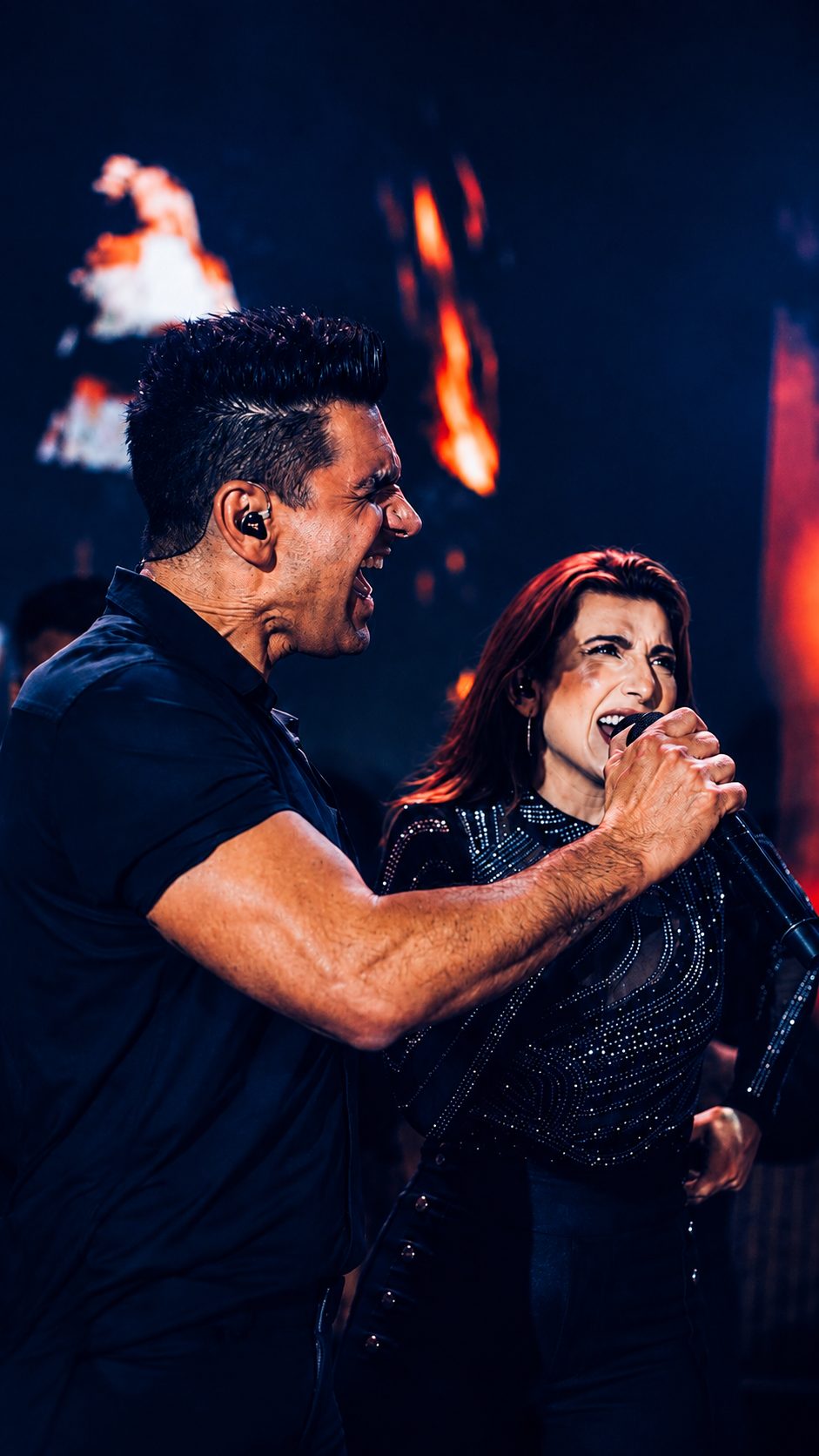 Cantor e cantora da Banda iNova em performance intensa com fundo de luzes