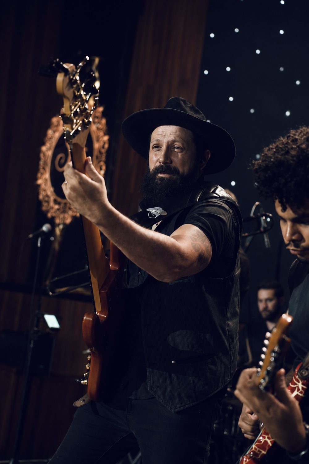 Baixista da Banda iNova de chapéu tocando ao vivo com a banda ao fundo